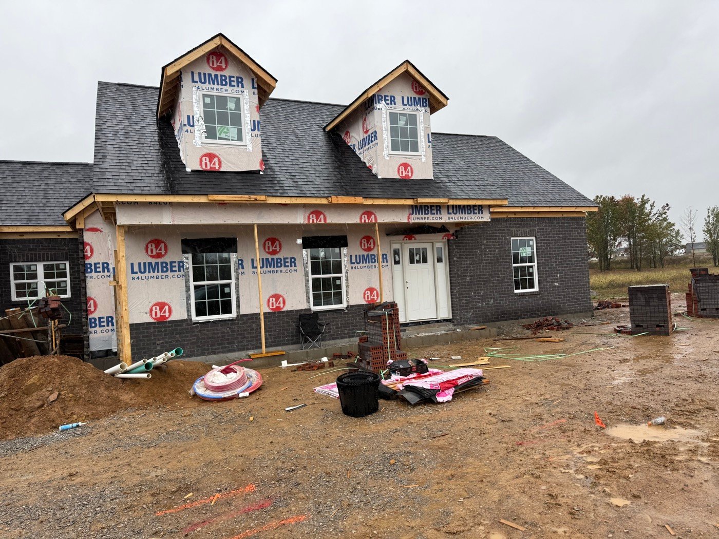 New brick home under construction with shingled roof